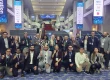 large group of people pose for photo in conference hotel lobby.
