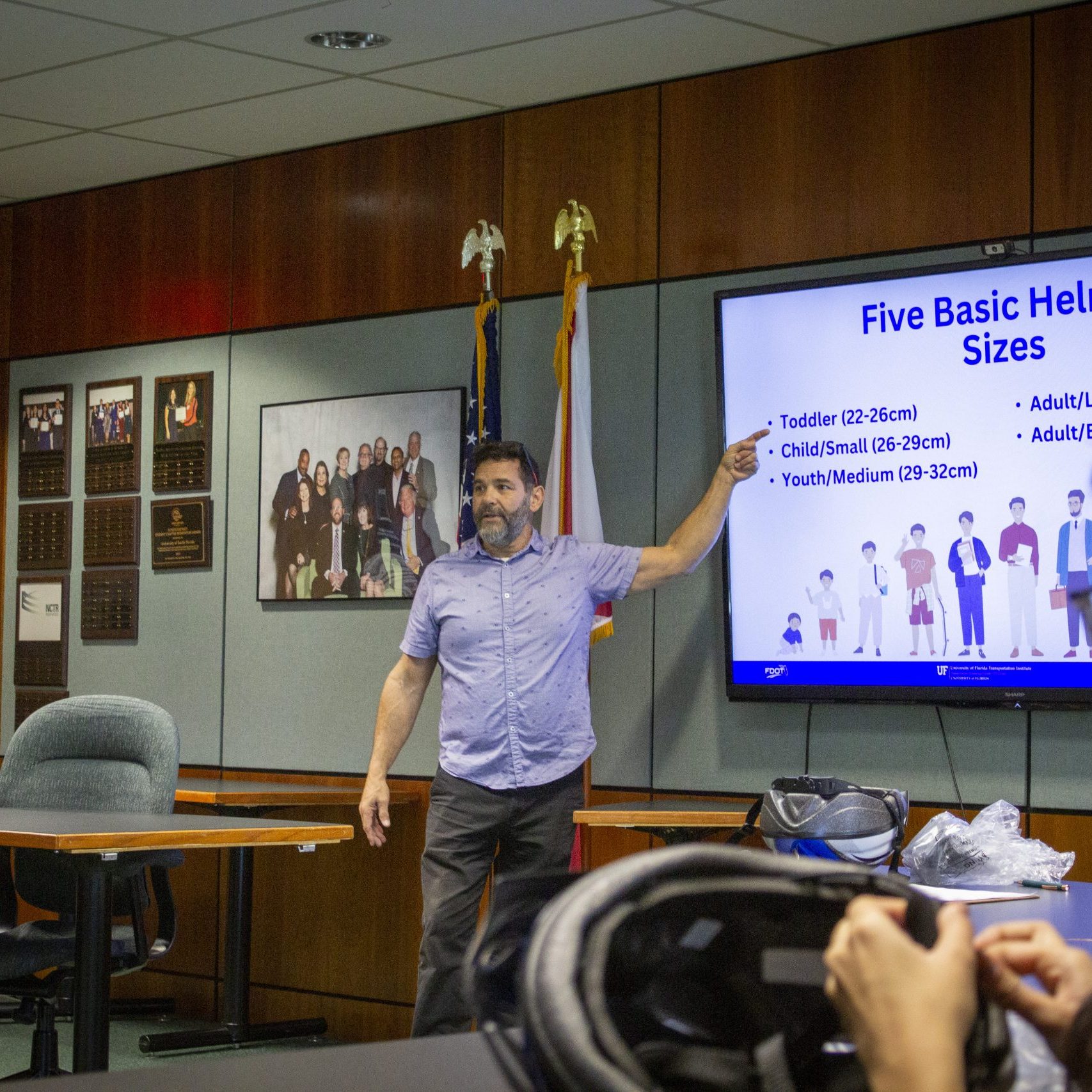 Male trainer points to a PowerPoint slide on a large screen.