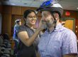 Female student practices fitting a bicycle helmet on an adult male. Her hands are adjusting the helmet straps of the helmet on his head.