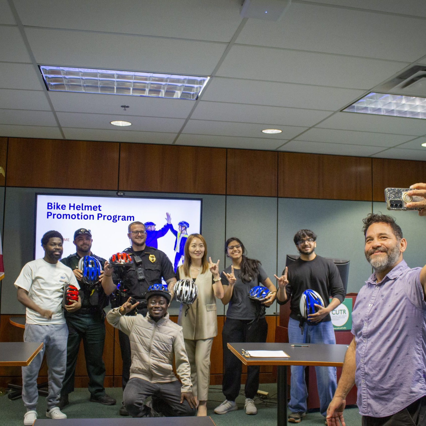 group of people stand together while a man at the front of the group takes a group selfie.