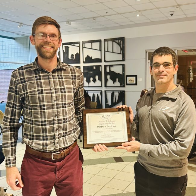 Matthew Dockins receives award Two men standing next to each other holding a certificate together.