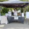 Outdoor community event. woman stands behind exhibitor table covered in informational materials and give-aways, holding flyers in her hands.