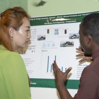130 woman looking at research poster while male student speaks about it