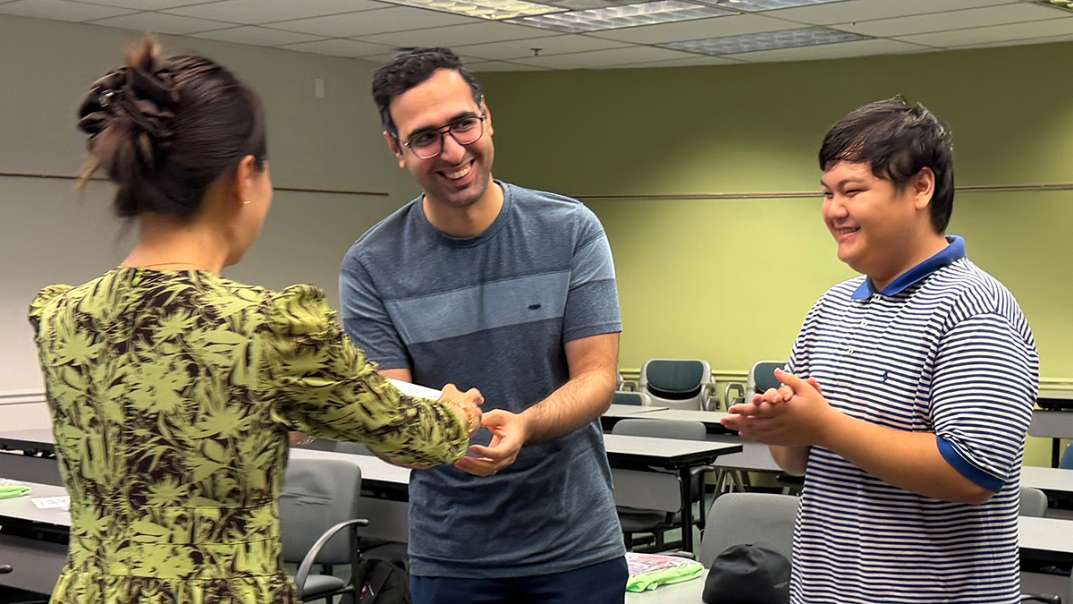 Presenter gives prize to one of two competitors during quiz game.