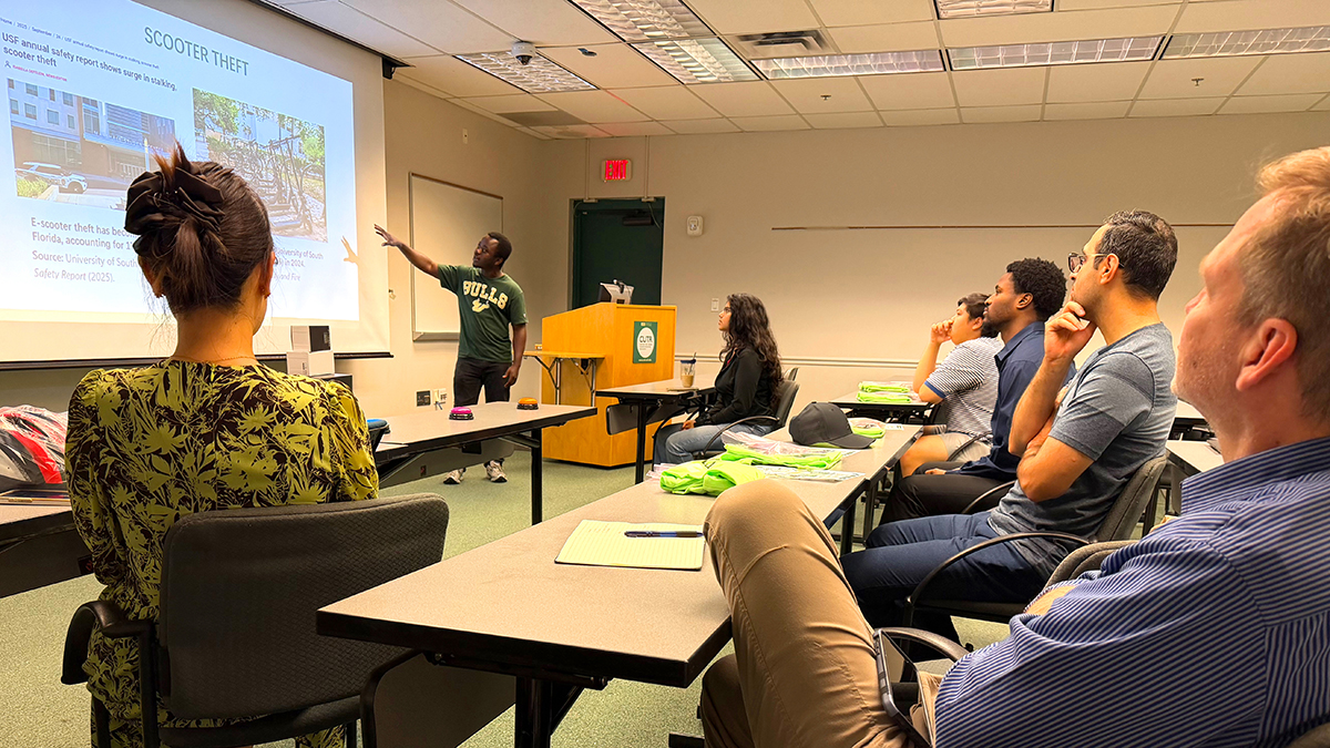 audience looks up at male presenting in front of PowerPoint slide