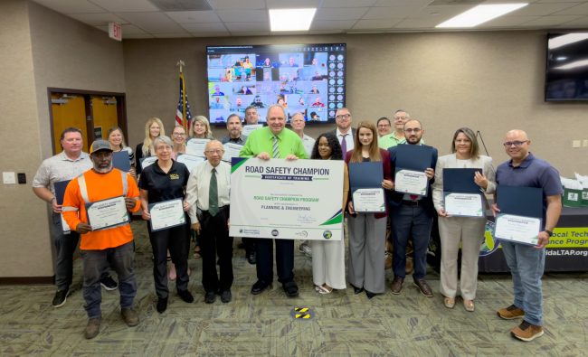 diverse group of adults stand together for a group photo holding their training certificates